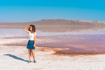 Portrait of a young woman on the background of a pink salt lake in Crimea on a Sunny day
