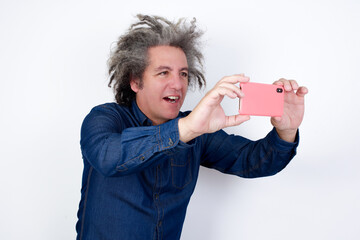 Handsome mature caucasian man with afro grey hair standing over isolated white background taking a...