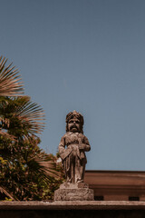 Kamienny posąg na włoskim ogrodzeniu, w tle piękne, błękitne niebo. 