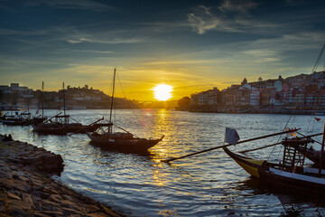 Sunset with boats carrying barrels of wine at Porto.