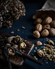 Nuts split on a wooden board with a nutcracker on a dark background.