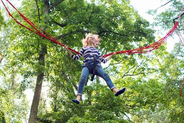 Teenager girl having fun jumping on trampoline with elastic ropes
