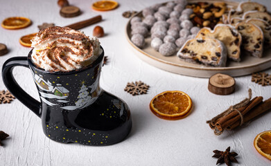 Winter hot drink in funny cup, cacao with Christmas stollen on wooden board with dried fruits and nuts. Traditional german cake.Concept for postcard, holiday greeting.