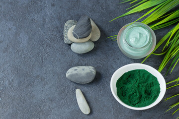 Spirulina powder on a dark background. Natural ingredient for spa treatments and cosmetology. Natural antioxidant. Anti-aging effect. Top view. Copy space.