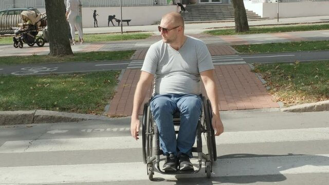 Handicapped man in wheelchair crossing street road