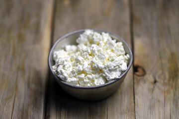 Selective focus. Fresh cottage cheese in an iron bowl. Rustic style.