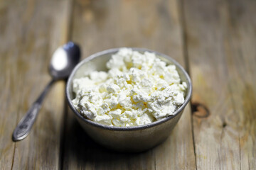 Selective focus. Fresh cottage cheese in an iron bowl. Rustic style.