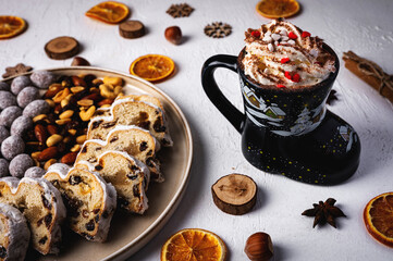 Winter hot drink in funny cup, cacao with Christmas stollen on wooden board with dried fruits and nuts. Traditional german cake.Concept for postcard, holiday greeting.