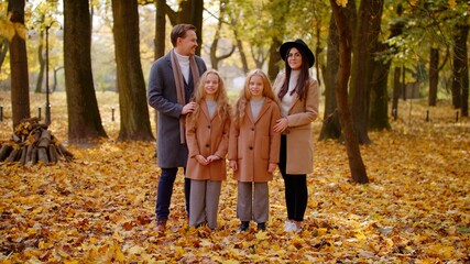 Naklejka na ściany i meble Portrait Of Happy Family On Autumn Walk. Mother Father and Children Twins In The Park Enjoying The Beautiful Autumn Nature. Friendly Family Kid Concept Autumn Countryside