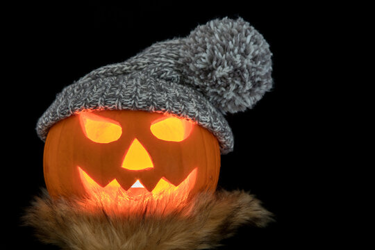 Halloween Pumpkin with Knitted Hat and Scarf on a Black Background