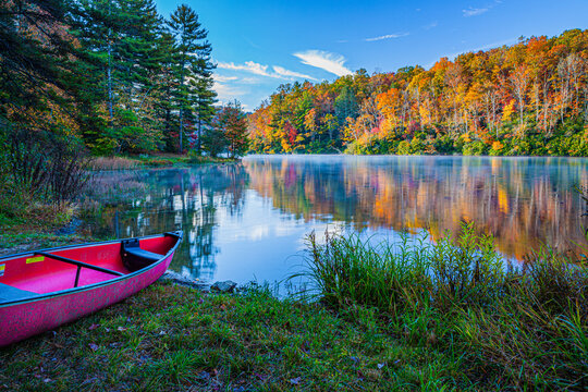 Pink canoe by colorful lake surrounded by fall colors in Smokey Mountains