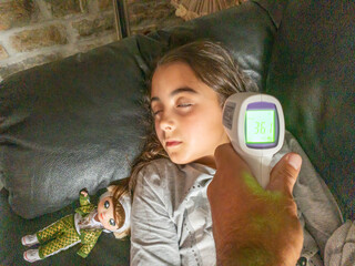Measuring young girl temperature with instant fever thermometer