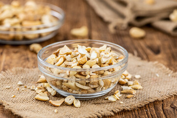 Wooden table with chopped Cashew nuts (close-up shots, selective focus)