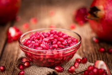 Some fresh preserved Pomegranate seeds on wooden background (selective focus; close-up shot)