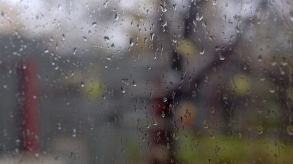 Cloudy weather and rain outside the window. Wet and misted window with dripping rain gums close up