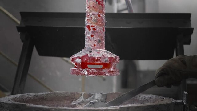 Worker removes slag from a barrel with molten metal