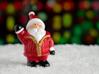 Festive decoration. Christmas toy Santa Claus waving his hand on the background with bokeh. Christmas New year concept