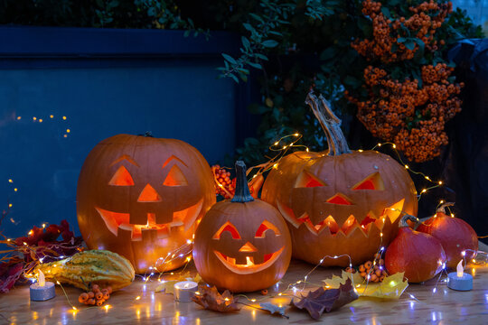 Smiling Halloween Jack-o-Lantern Pumpkins on rustic wooden background.