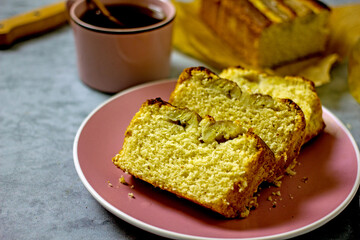 Banana cake gluten free and sugar free for breakfast. Pieces of banana bread on a pink plate on a gray table, next to a cup of tea, honey. Healthy nutrition concept