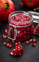 Fresh made preserved Pomegranate seeds on a slate slab (close-up shot; selective focus)