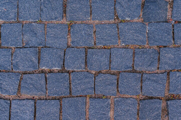Cobblestone road for background and texture. Old road made of granite paving stones.