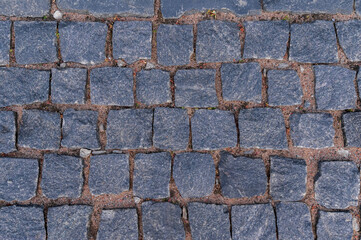 Cobblestone road for background and texture. Old road made of granite paving stones.