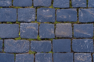 Cobblestone road for background and texture. Old road made of granite paving stones.