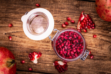 Some fresh preserved Pomegranate seeds on wooden background (selective focus; close-up shot)
