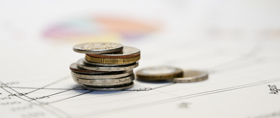 Closeup of three stacks of silver coins on the graphs and business charts.Concept of financial analyzing of budget and sales