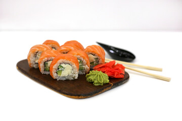 Philadelphia rolls with salmon on white table next to chopsticks, wasabi and ginger. Sushi menu. Japanese food concept