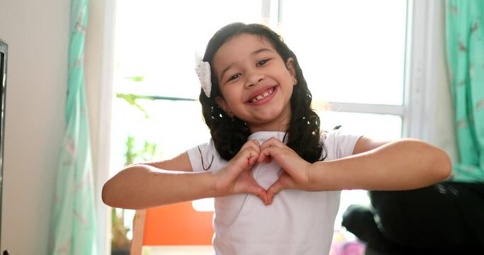 Adorable child making heart symbol with hands
