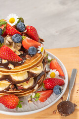 Pancakes with chocolate paste and hazelnuts, banana, strawberry and blueberry