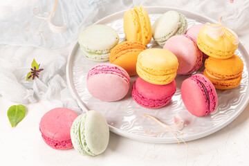 Colorful french macaroon cakes. Macaroons with jasmine flowers on white table background. Selective focus