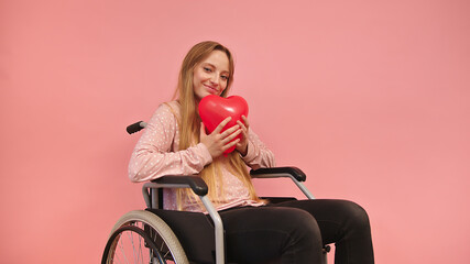 Young caucaian disabled woman in wheelchair holding heart balloon. High quality photo