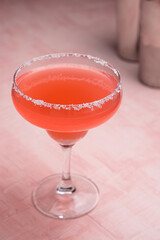 Red Margarita cocktail and some bartender accessories on a pink background