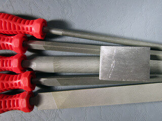 metal files with red handles and metal block in various shapes on gray background .. industry ...