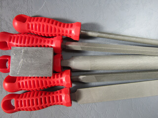 metal files with red handles and metal block in various shapes on gray background .. industry ...