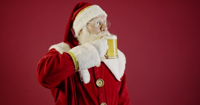 Santa Claus drinking a glass of beer. Rest time. Alcoholic drink at the holidays. Drink with moderation. Craft beer. Merry Christmas. 4K.
