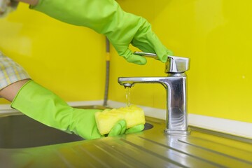 Close-up of cleaning kitchen, woman's hands in rubber gloves with sponge