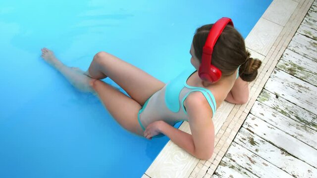 Beautiful young woman listening to music in swimming pool 