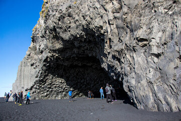REYNISFJARA, VÍK, ICELAND - SEPTEMBER 20, 2018: Tourists at Reynisfjara, a black-sand beach with hexagonal-shaped basalt columns and caves during a beautiful sunny autumn day.
