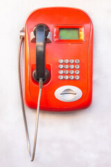 red landline phone with buttons on the wall
