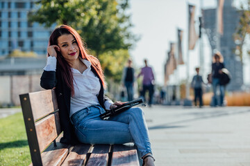 Fototapeta premium Beautiful businesswoman with red hair working oh tablet outdoor.