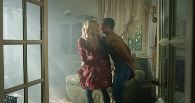 Cinematic shot of young carefree happy smiling homosexual female gay and transgender man couple in love is enjoying time together and having fun to dance together while listening to the music at home