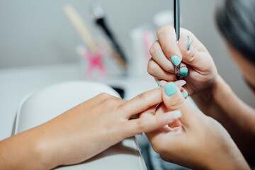 Young woman getting a beautiful manicure in the salon. The process of making nails.