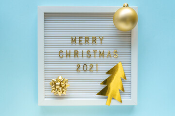 Letter board with Merry Christmas 2021 greeting, decorations on blue pastel backdrop. Christmas composition. Flat lay, from above