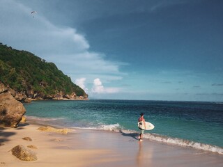 The surfer guy with his board ready to ride the wave at the blue ocean and white sandy beach
