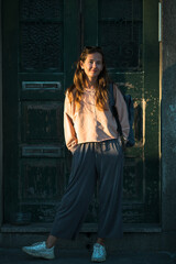 A young woman poses against the background of the old doors of the house.