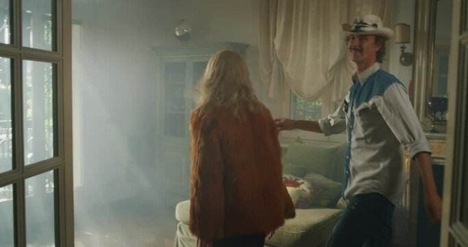 Cinematic shot of young carefree happy smiling homosexual male gay and transgender woman couple in love is enjoying time together and having fun to dance together while listening to the music at home.