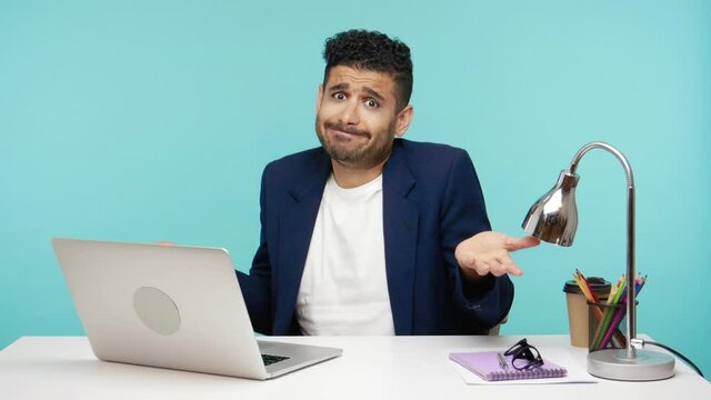 Uncertain Confused Business Man Shrugging Shoulders And Throwing Up His Hands, Dont Know Answers On Questions. Indoor Studio Shot Isolated On Blue Background